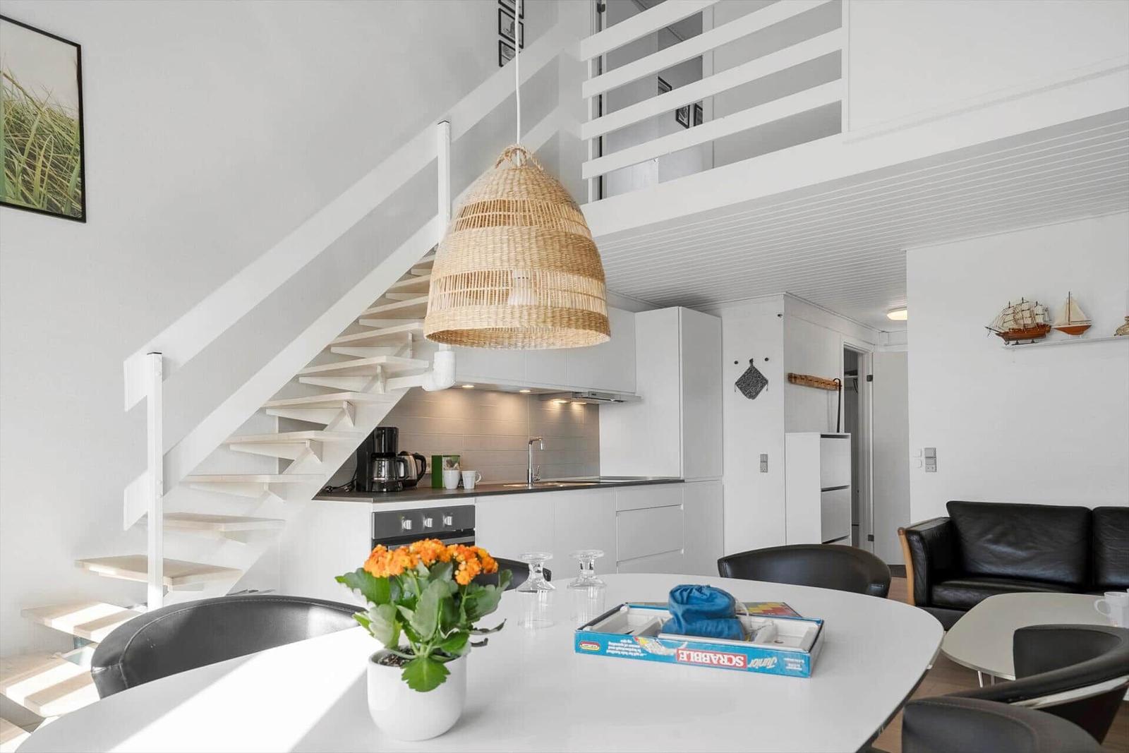 Küche mit Essbereich, Treppenhaus und Wohnzimmer im Hintergrund.