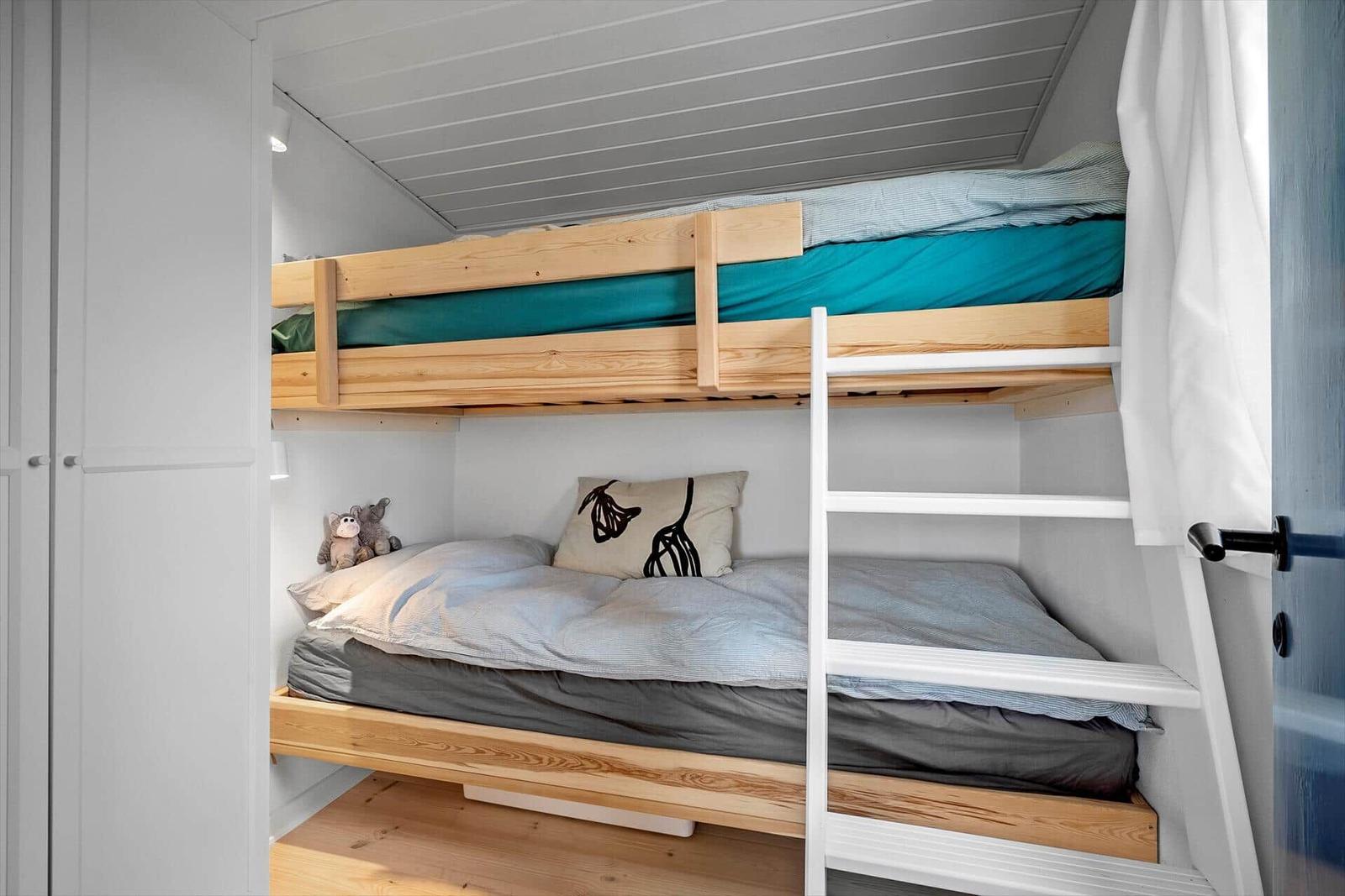 Ein Schlafzimmer mit einem Doppelstockbett aus Holz und einer weißen Leiter.