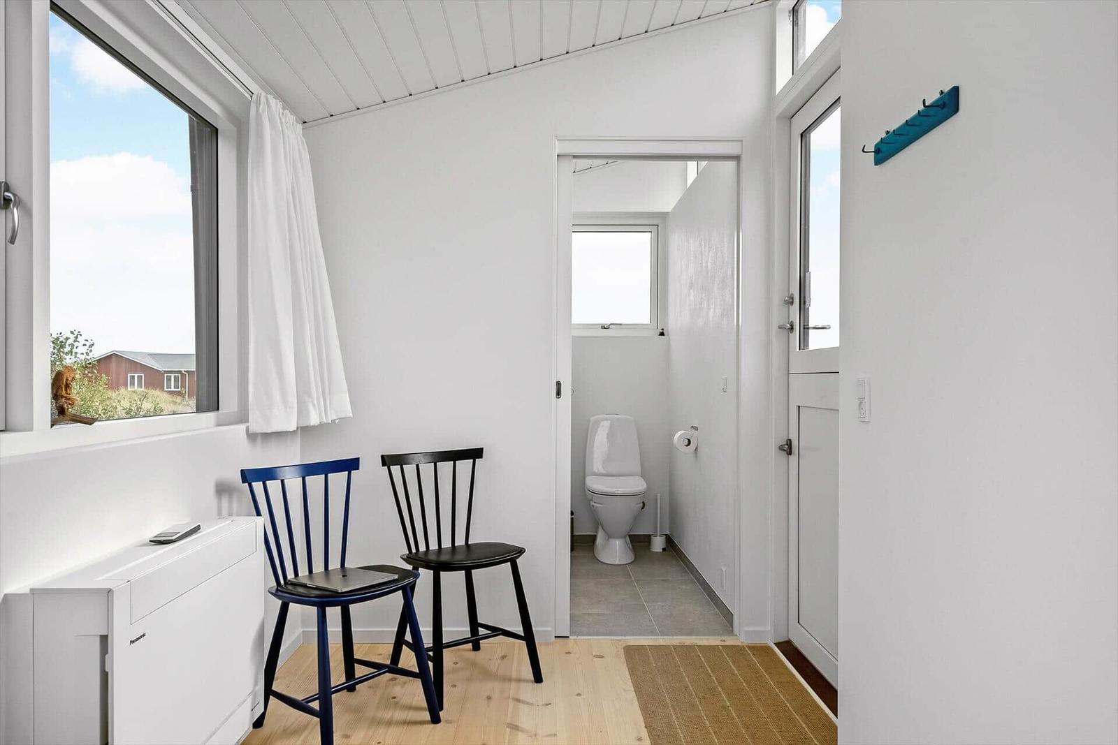 Zimmer mit zwei Stühlen, Fenster und Tür zum Bad.