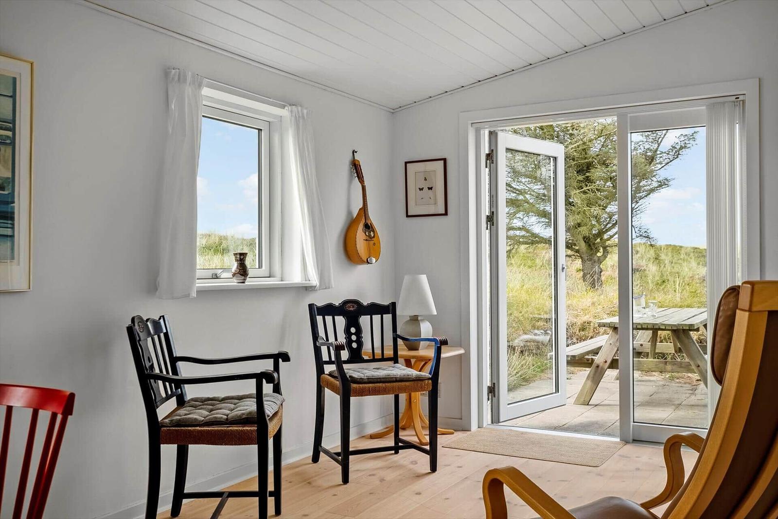 Raum mit Stühlen, Fenster und Tür zu einem Außenbereich mit Tisch.