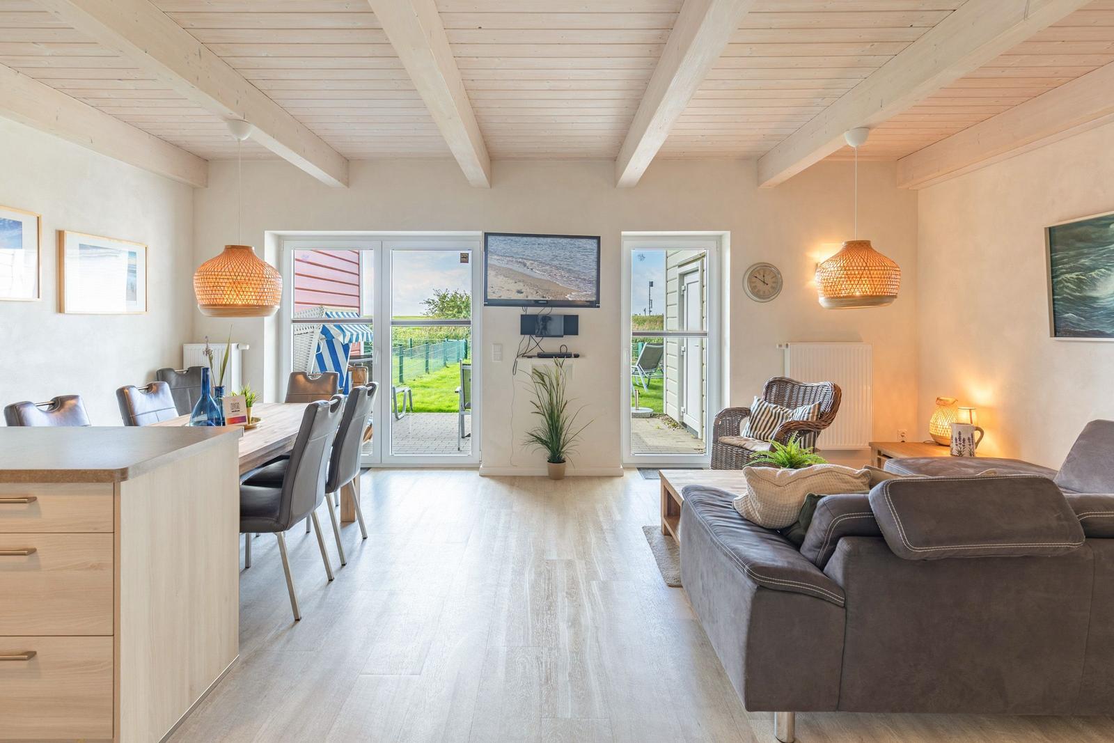 Living and dining area with wooden ceiling, TV, and terrace.