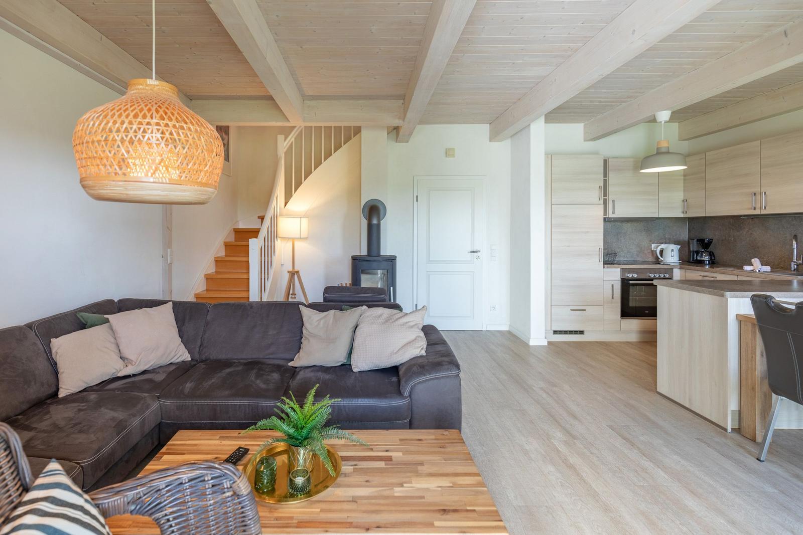 Living area with sofa, kitchenette, and wooden ceiling.