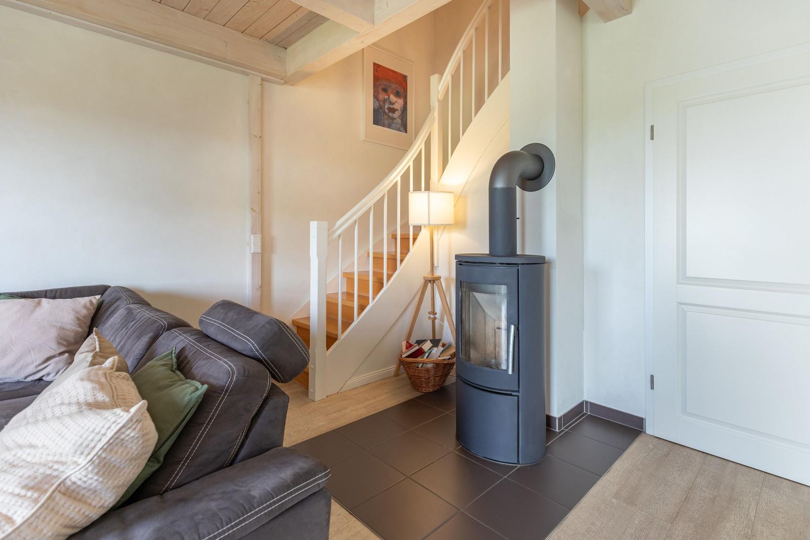 Living room with sofa, wood stove, and staircase.