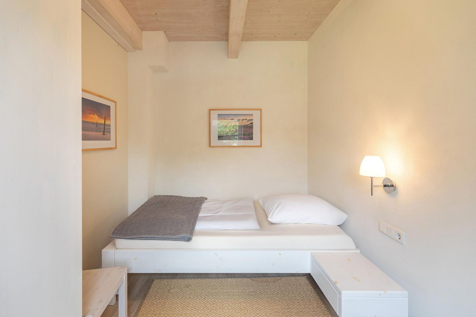 Bedroom with bed, wall lamp, and pictures on the walls.