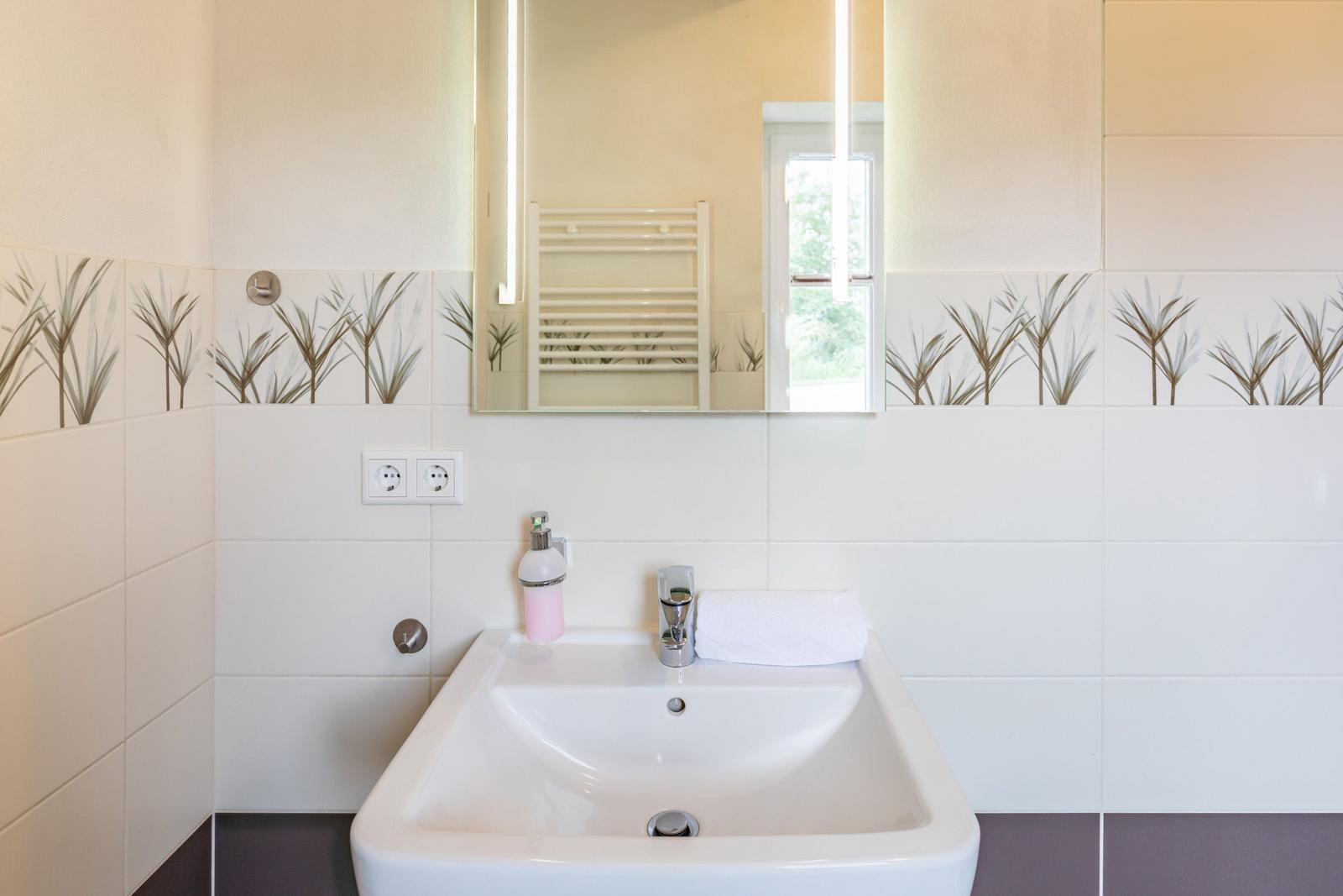 Bathroom with sink, mirror, and heater.