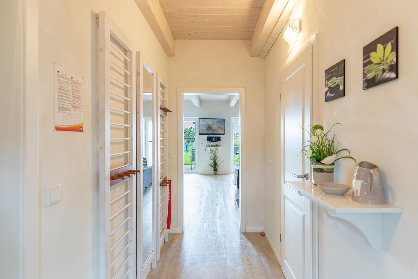 Hallway with coat rack, plant, and pictures on the wall. Corridor leading to the living area.