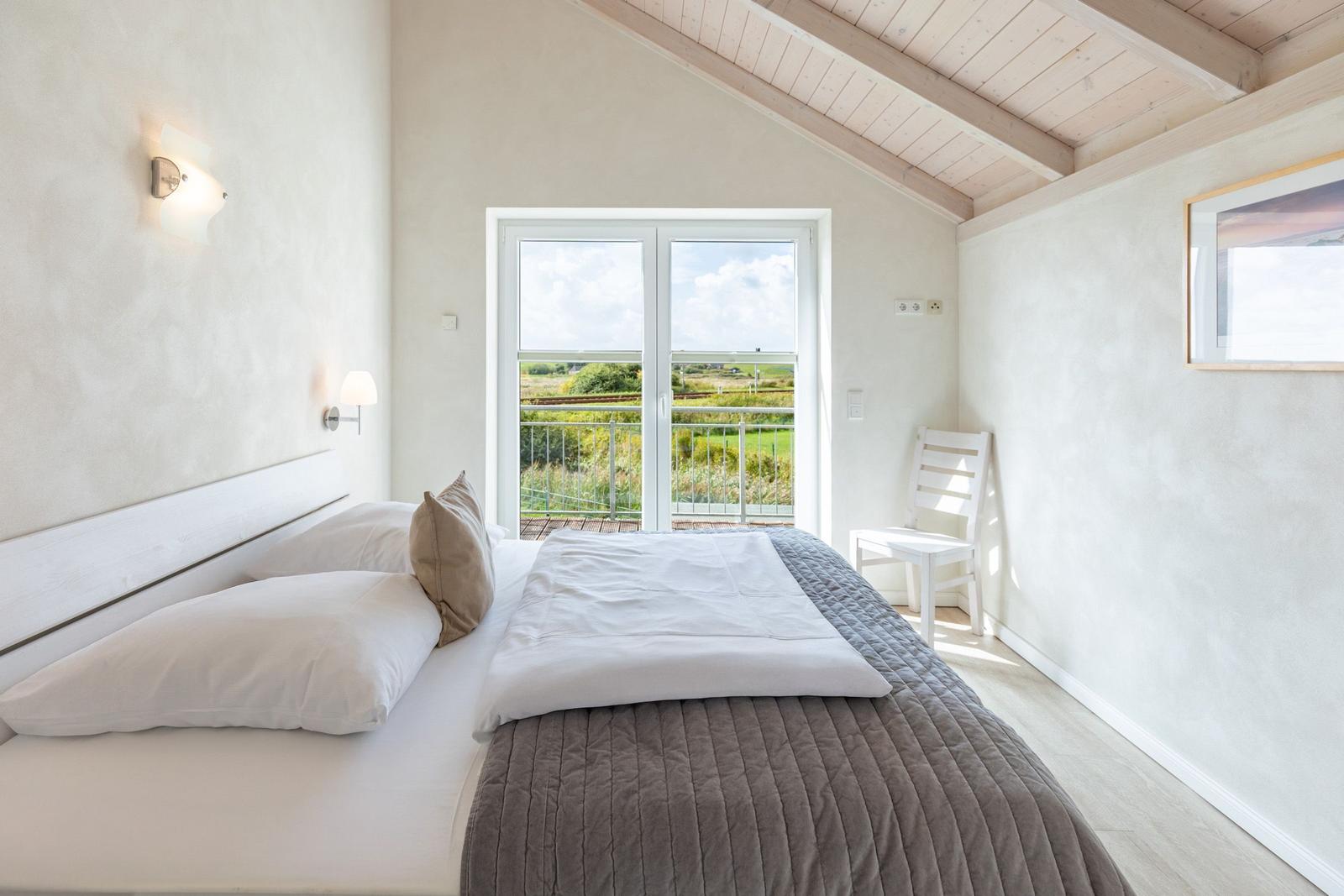 Bedroom with bed, window and chair. View of green landscape.
