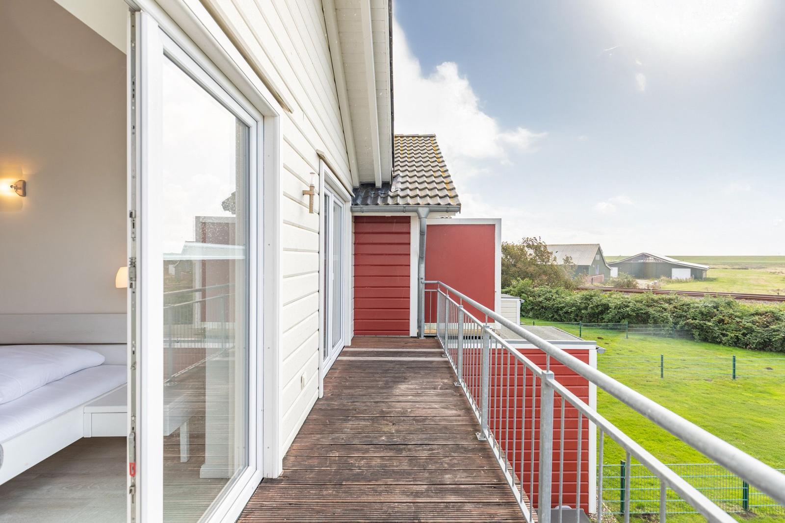 Deck with view of green field and red sheds