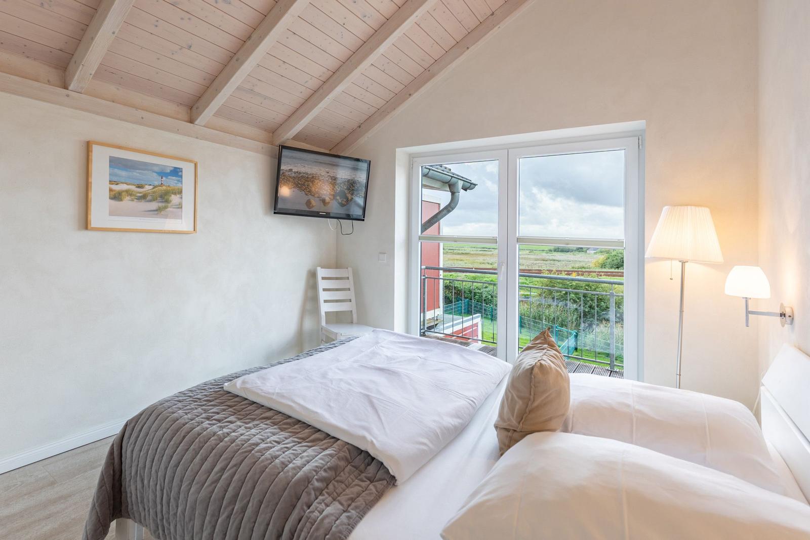 Bedroom with bed, TV, and balcony view.