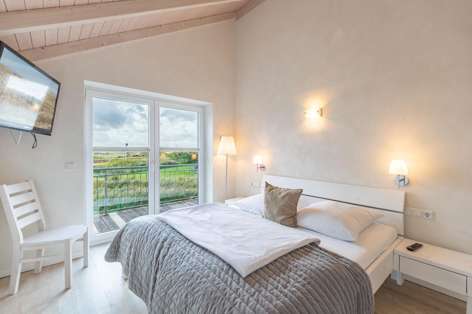 Bedroom with bed, TV, and balcony view.