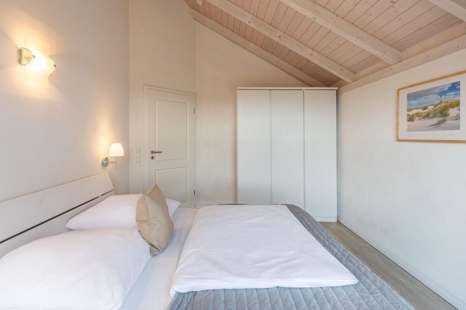Bedroom with double bed, wardrobe, and wooden ceiling.