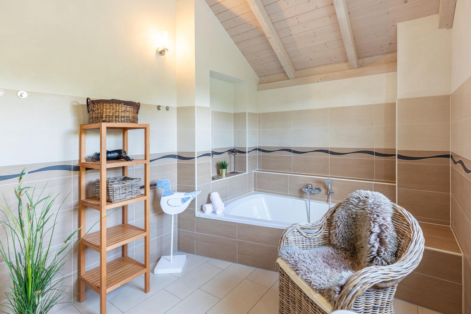 Bathroom with bathtub, wicker chair, and wooden shelf on the wall.