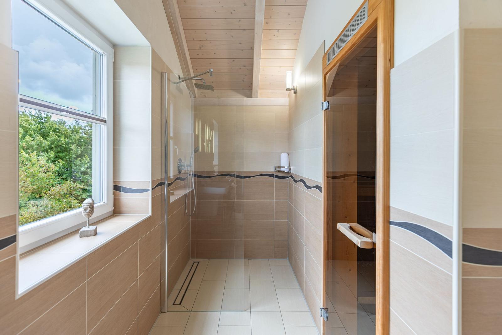 Bathroom with shower, sauna, and window with view of nature.