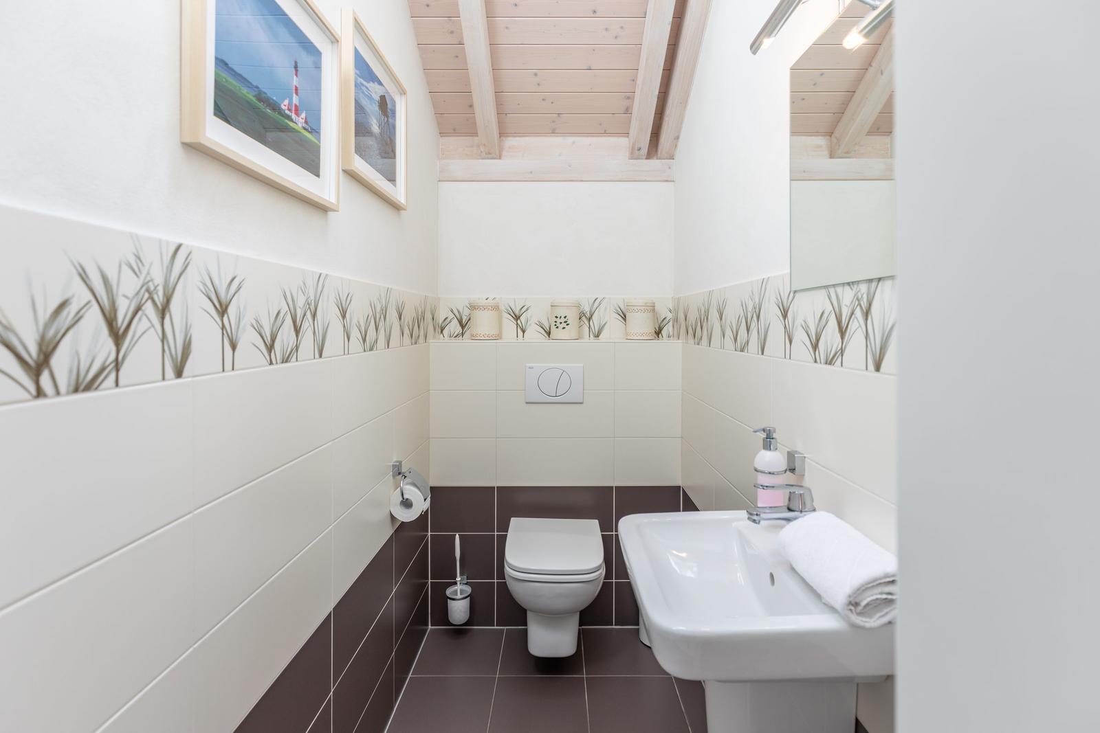 Bathroom with toilet, sink, and wooden ceiling.