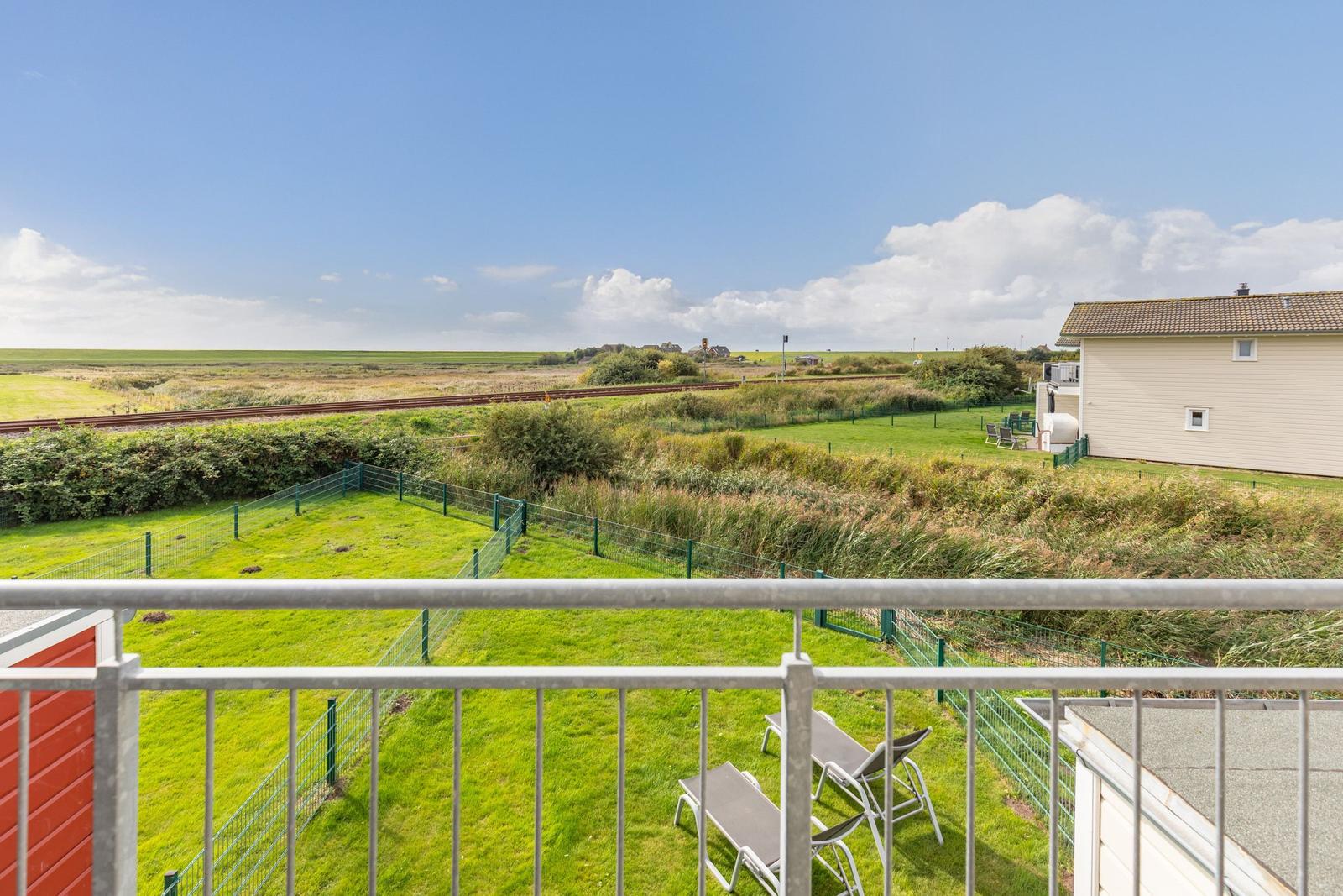Terrace with sun loungers and view of green areas and railway line.