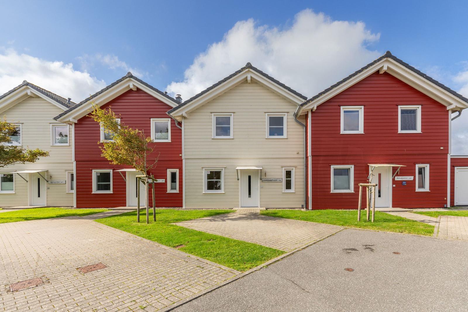 Four houses with red and cream facades under a blue sky.