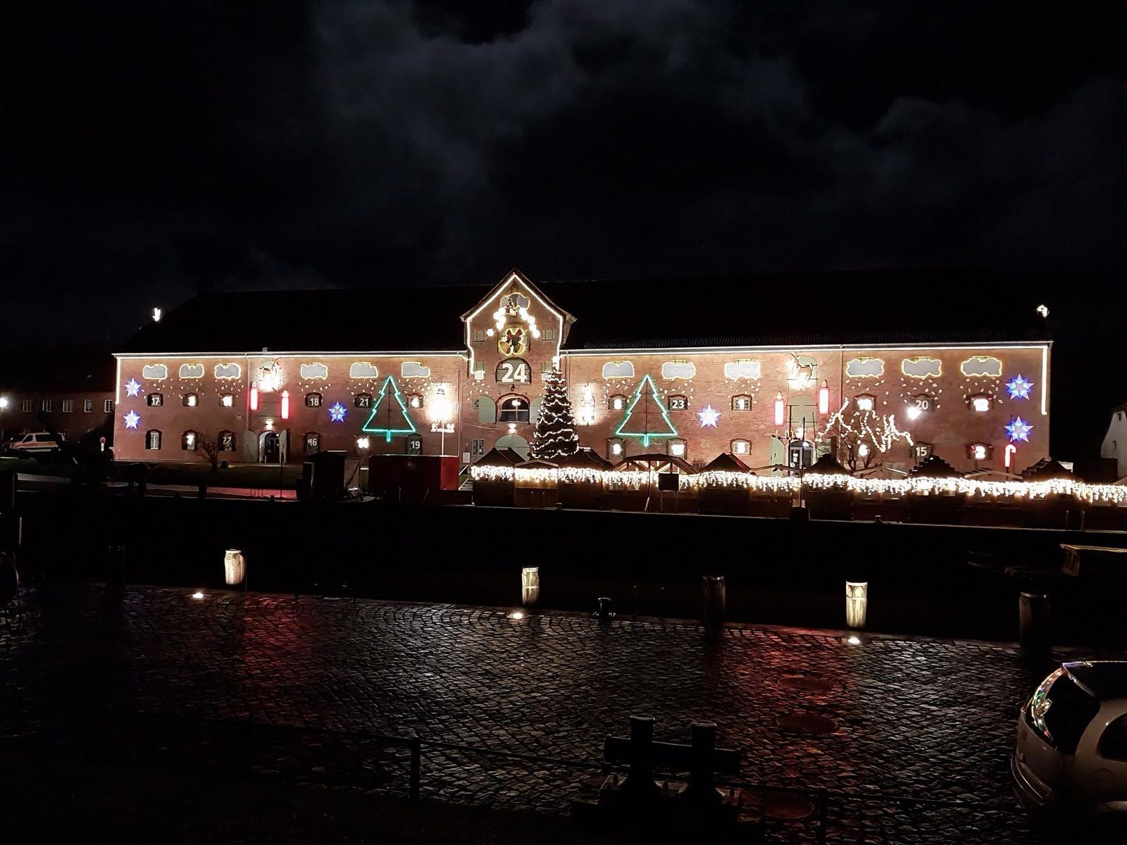 Festlich beleuchtetes Gebäude mit Weihnachtsdekoration und Adventskalender an der Fassade.