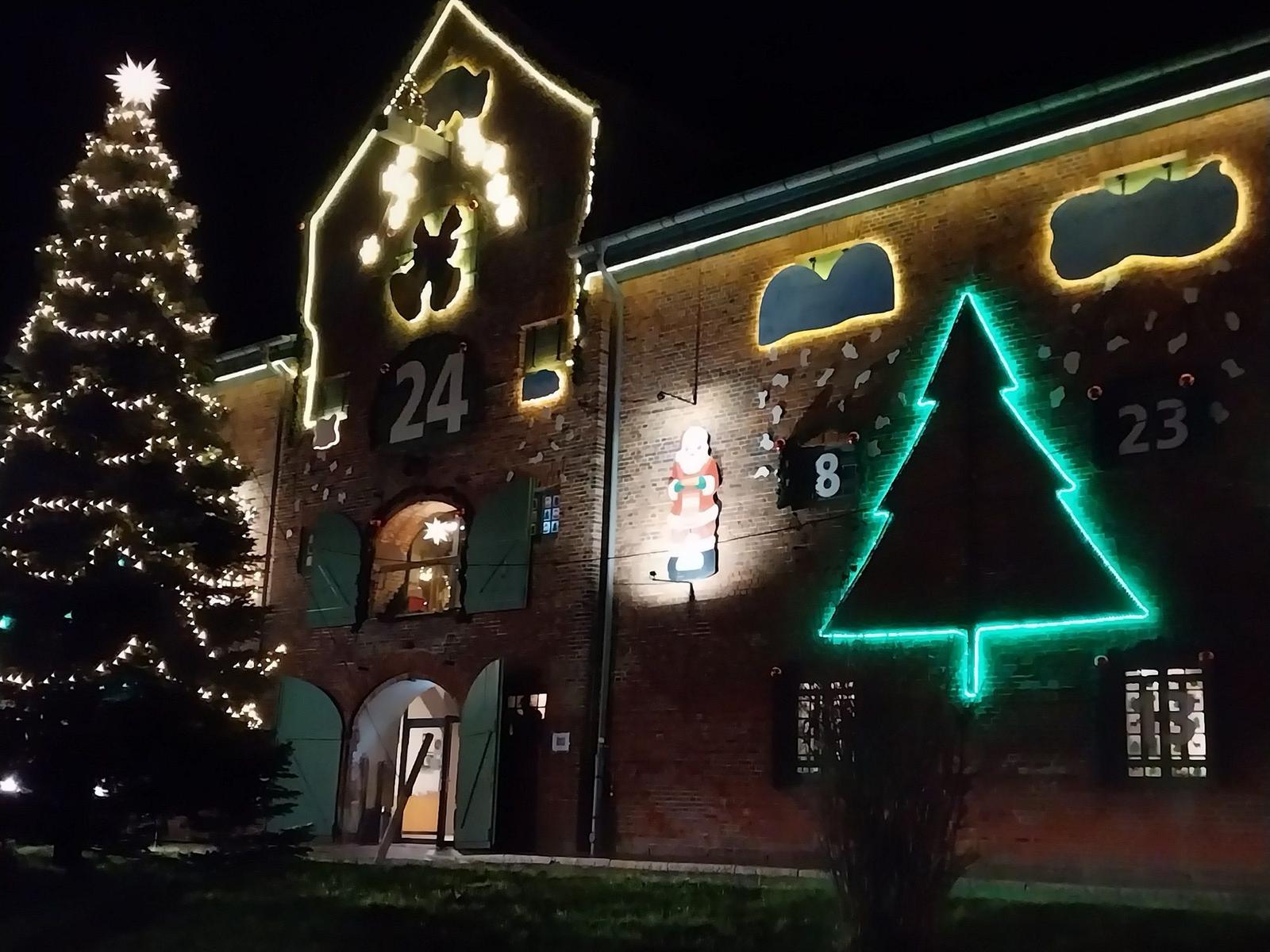 Festlich beleuchtetes Gebäude mit Weihnachtsbaum und Nikolausdekoration.