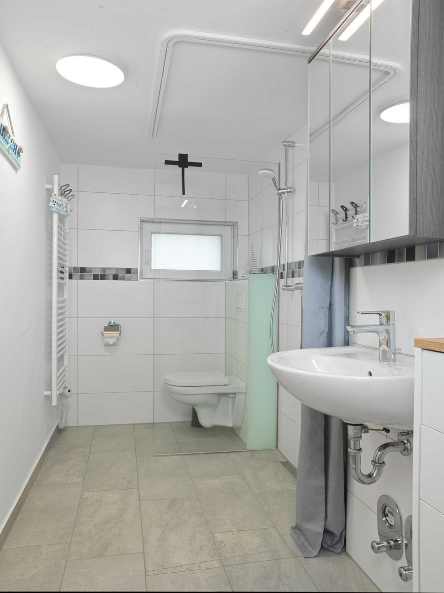 Badezimmer mit Dusche, WC und Waschbecken.