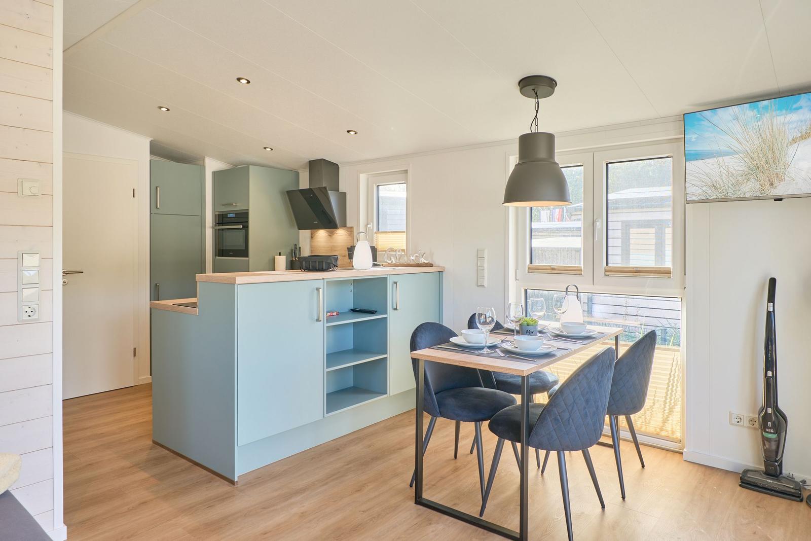 Küche mit Essbereich, blauer Arbeitsplatte und Fenster zur Terrasse.