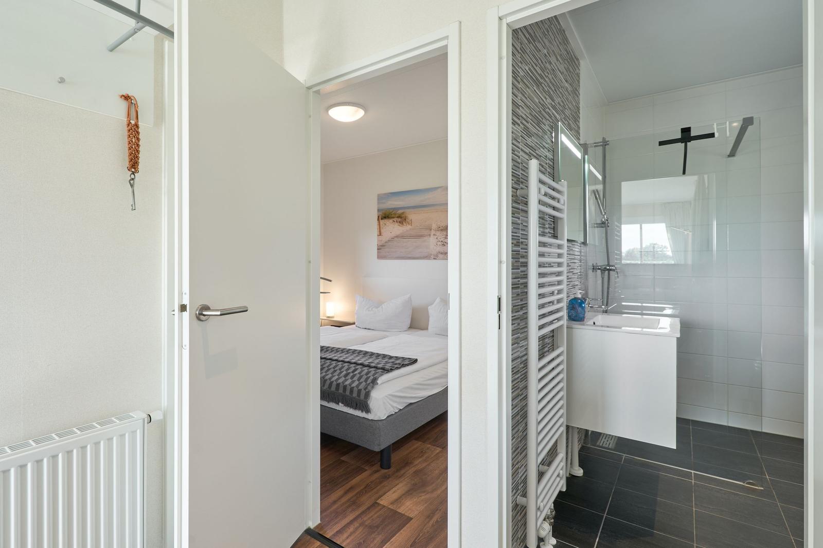 Schlafzimmer mit Bett und Bad mit Dusche und Waschbecken