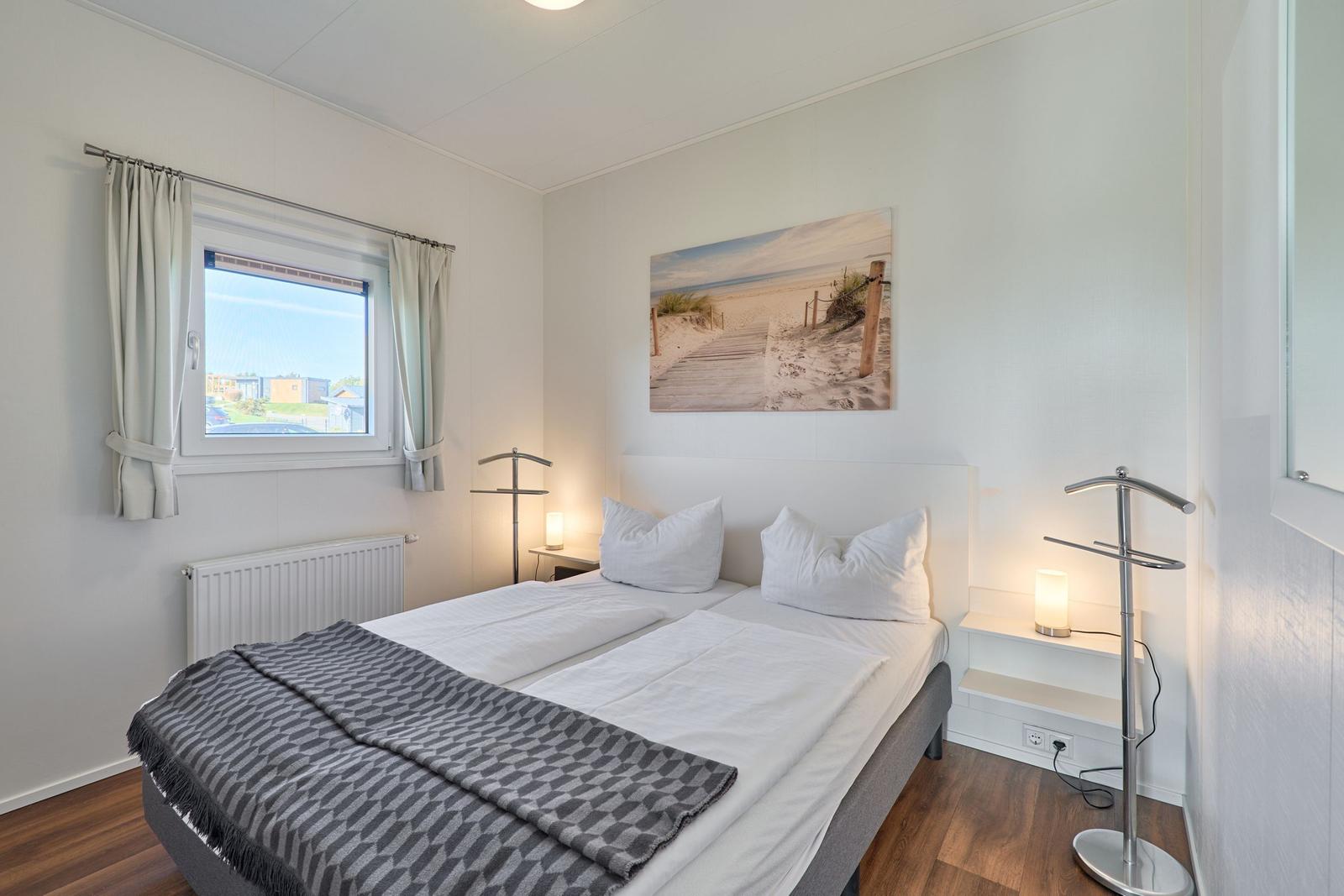 Schlafzimmer mit Bett, Fenster und Wandbild.