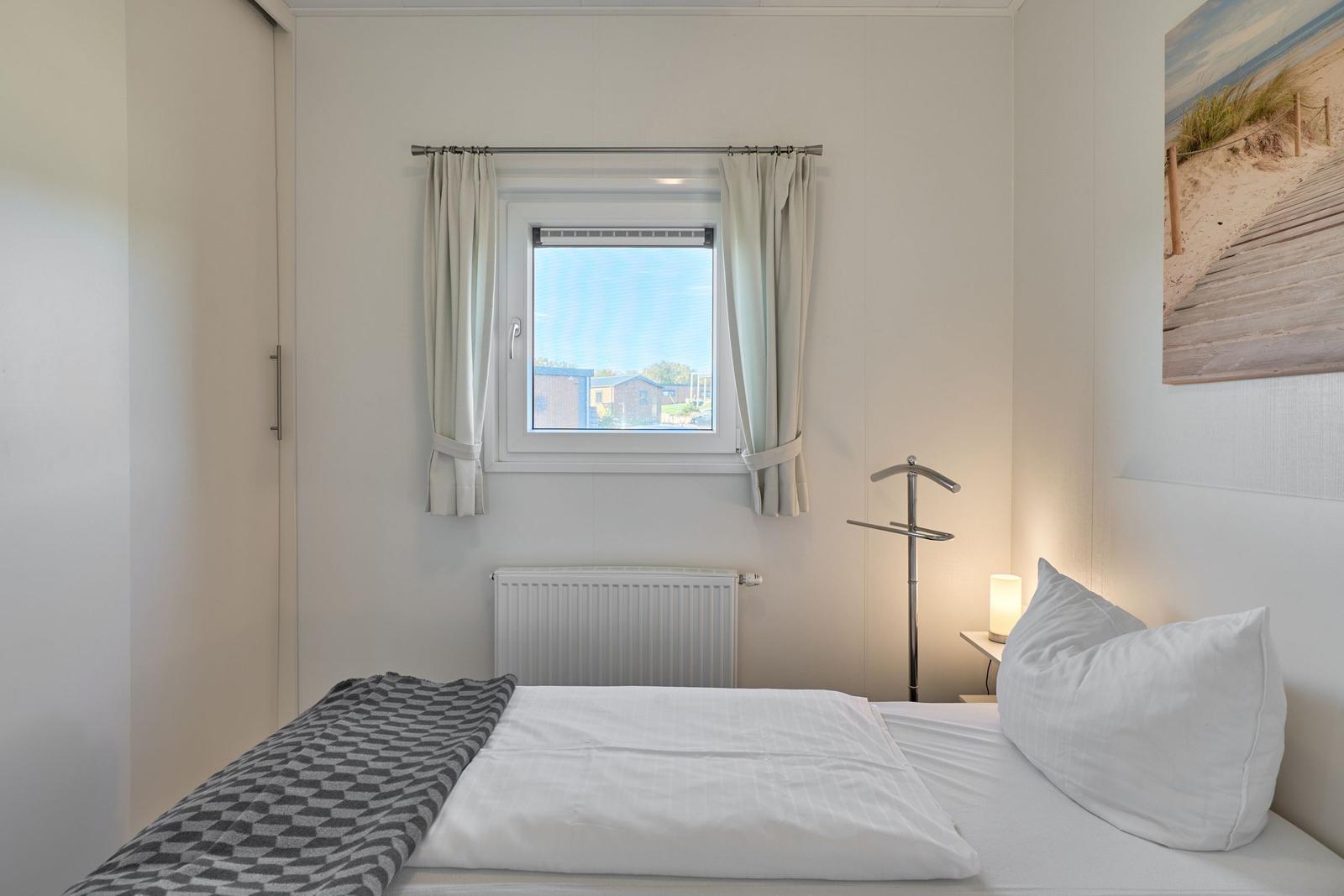 Schlafzimmer mit Bett, Fenster und Wandbild.