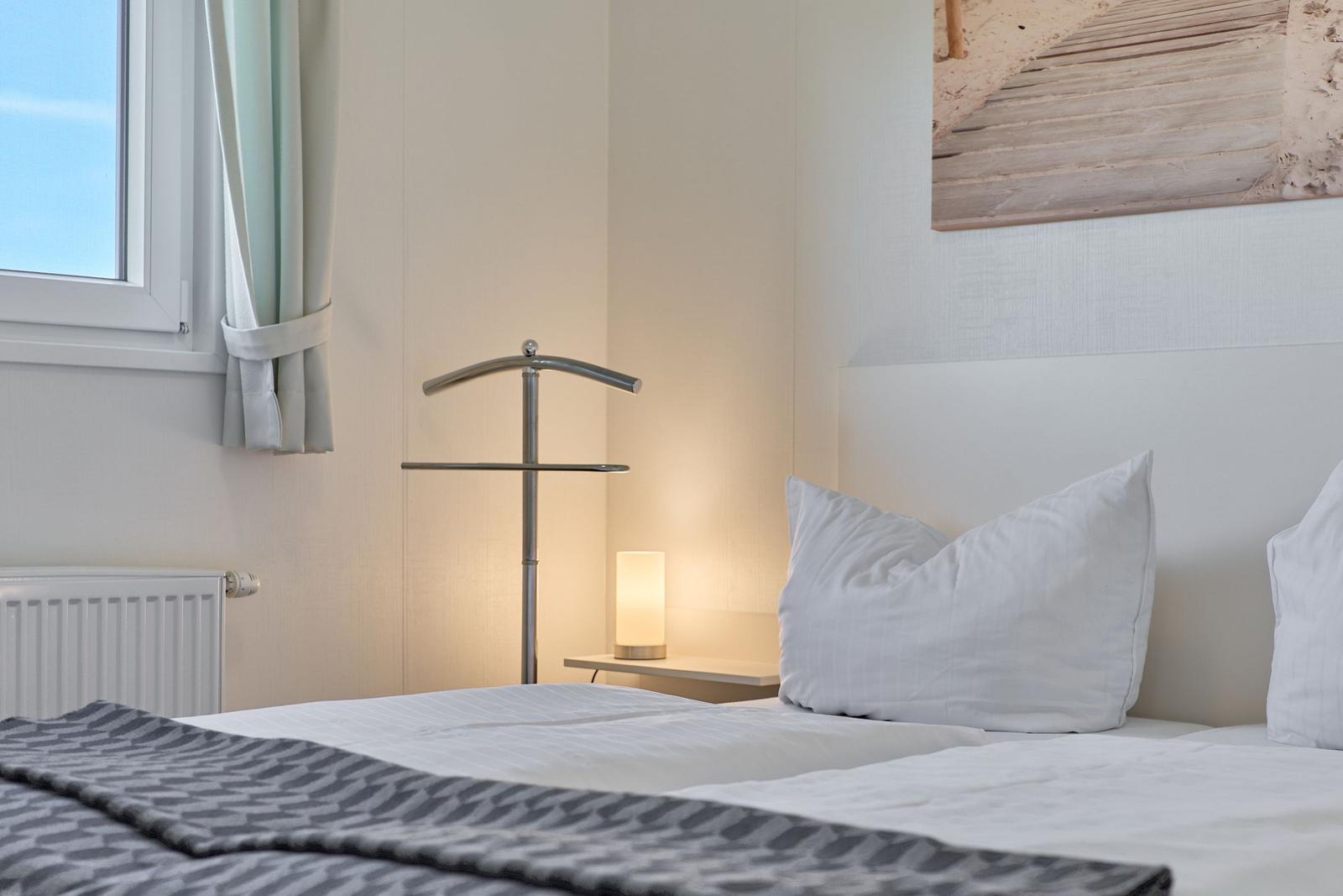 Ein Bett mit weißen Kissen und einer grauen Decke. An der Wand hängt ein Bild.