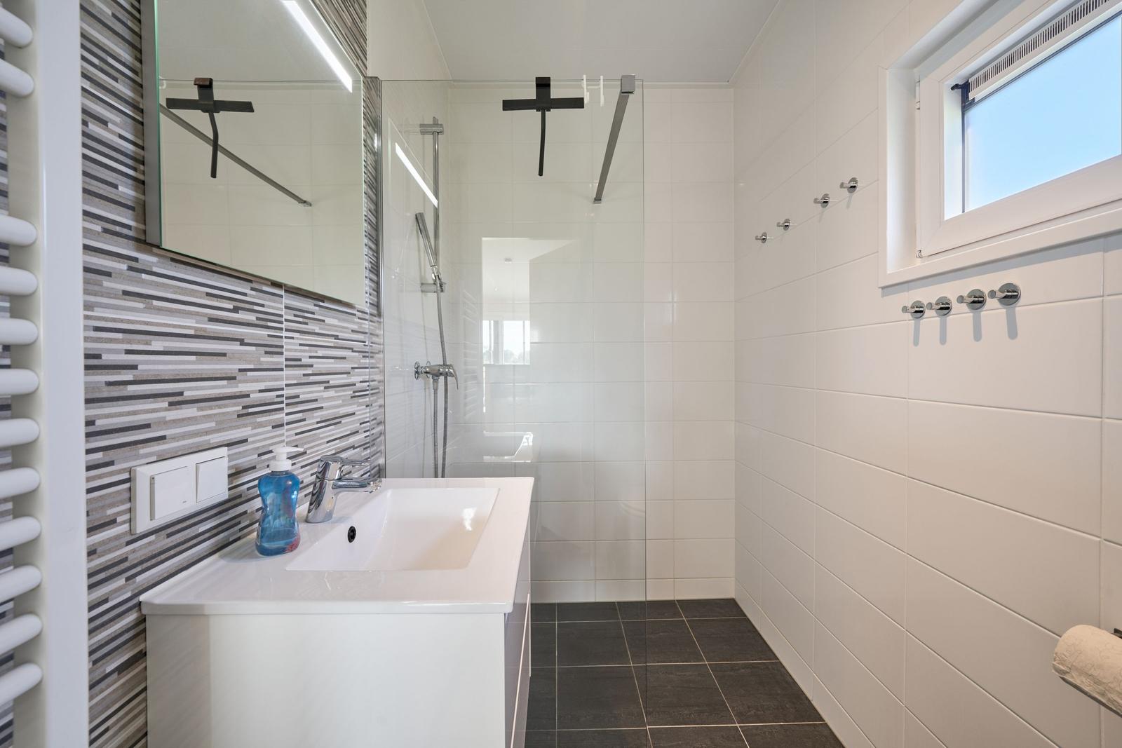 Badezimmer mit Dusche, Waschbecken und Fenster