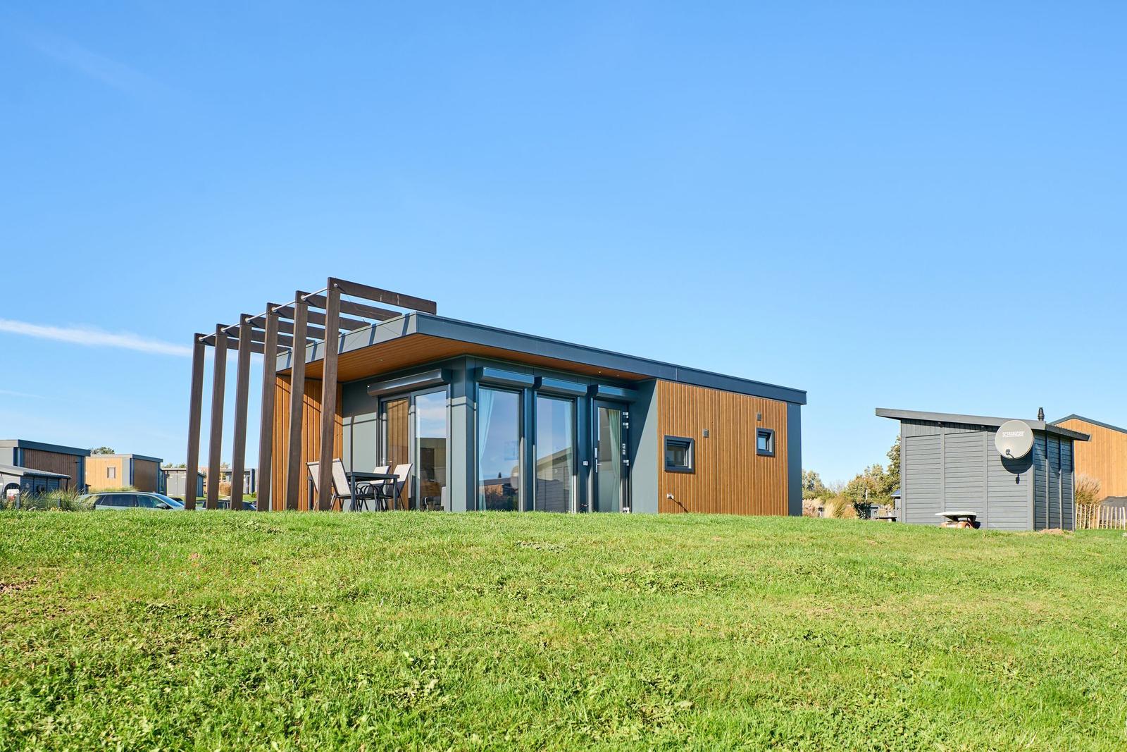 Moderne Ferienhaus mit Terrasse und Garten. Nebenhaus mit Satellitenschüssel.