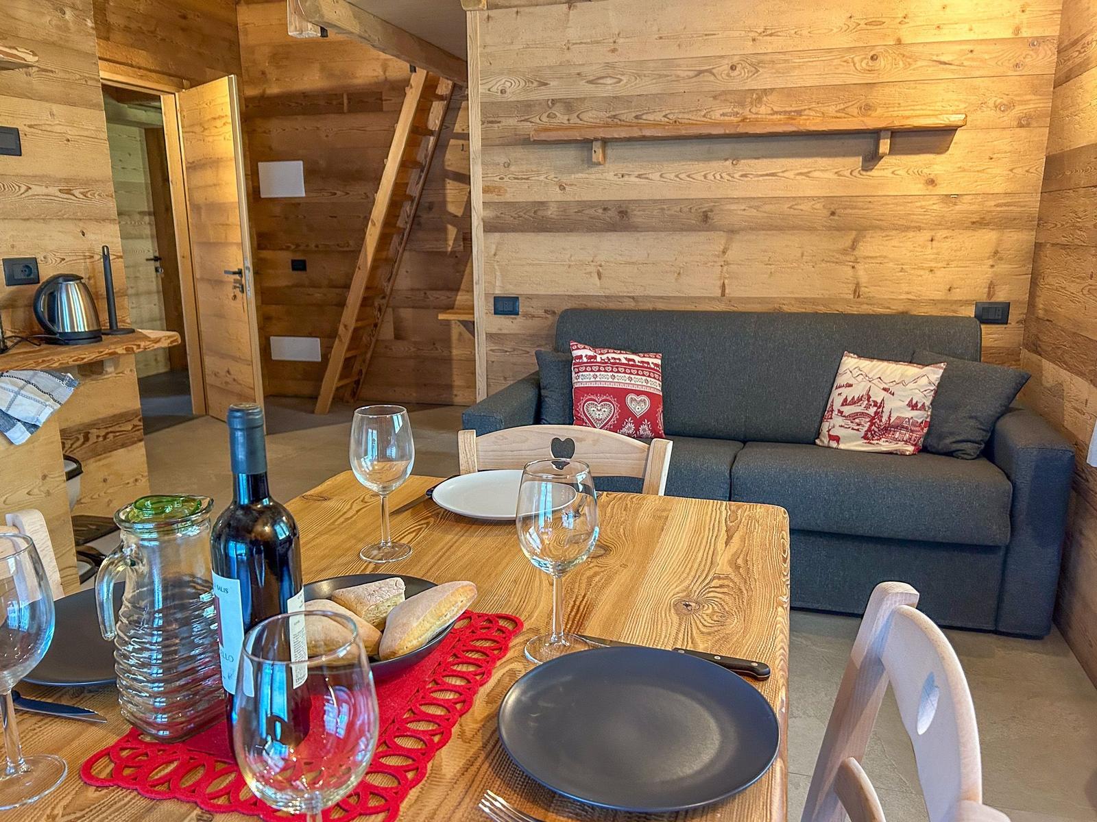 Holzgetäfelte Wohnung mit Sofa, Esstisch und Küchenbereich.