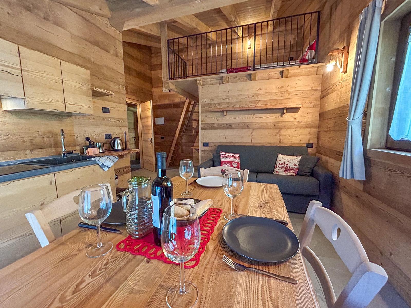 Essbereich mit Tisch, Stühlen und Sofa. Obergeschoss mit Balkon und Holzwände.