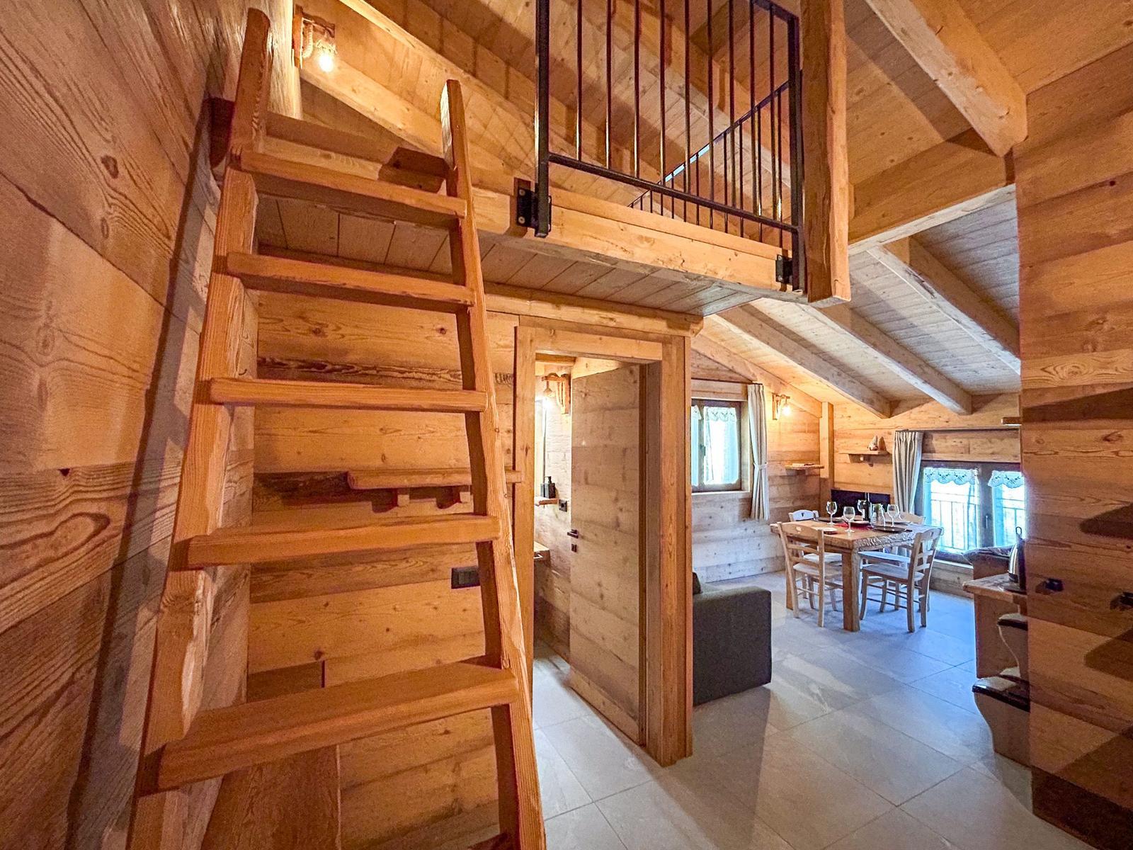 Holztreppe führt zu einer Galerie über dem Essbereich mit Tisch und Stühlen.