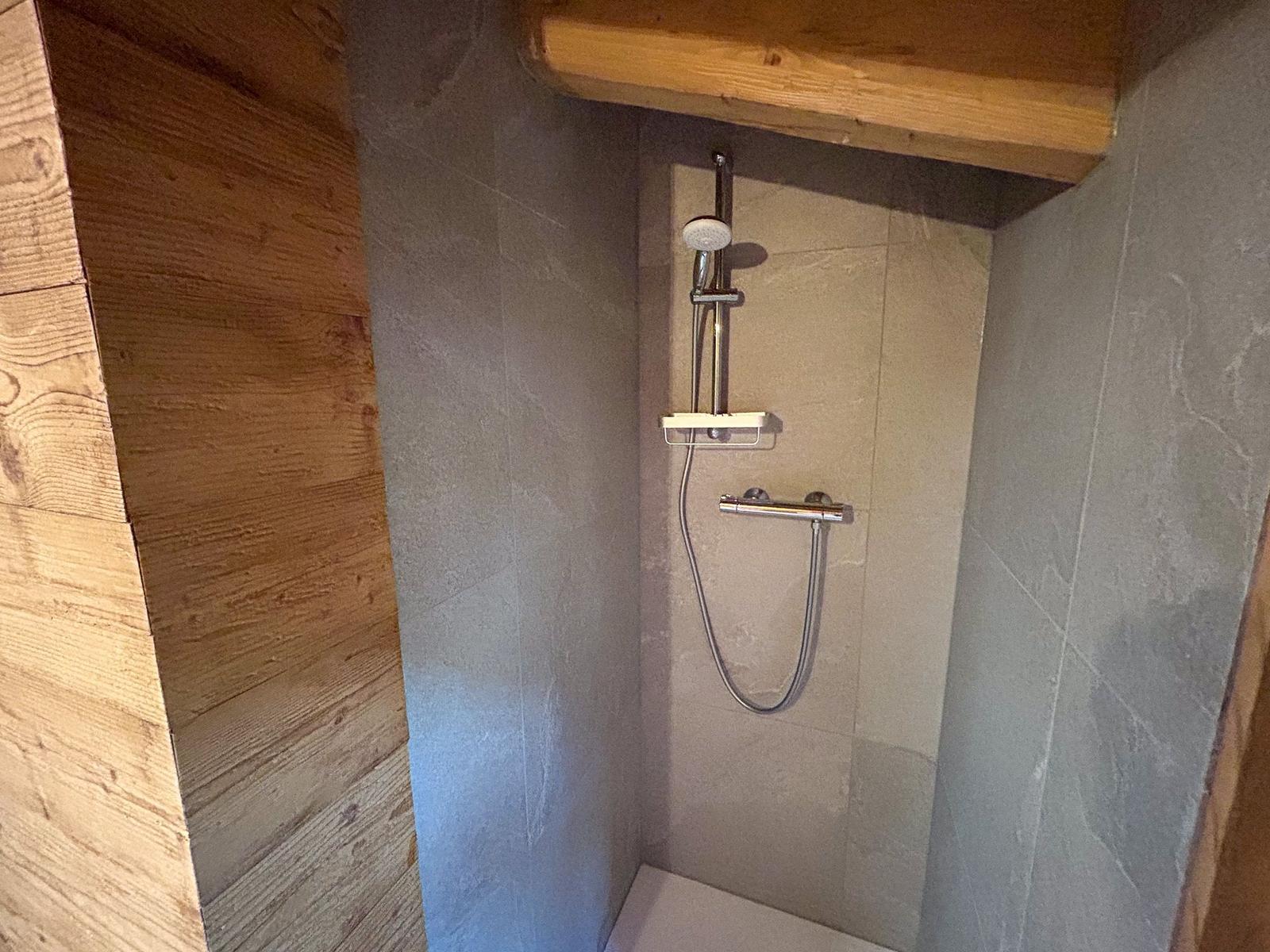 Dusche mit Duschbrause und Handbrause, Wandverkleidung aus Stein und Holz