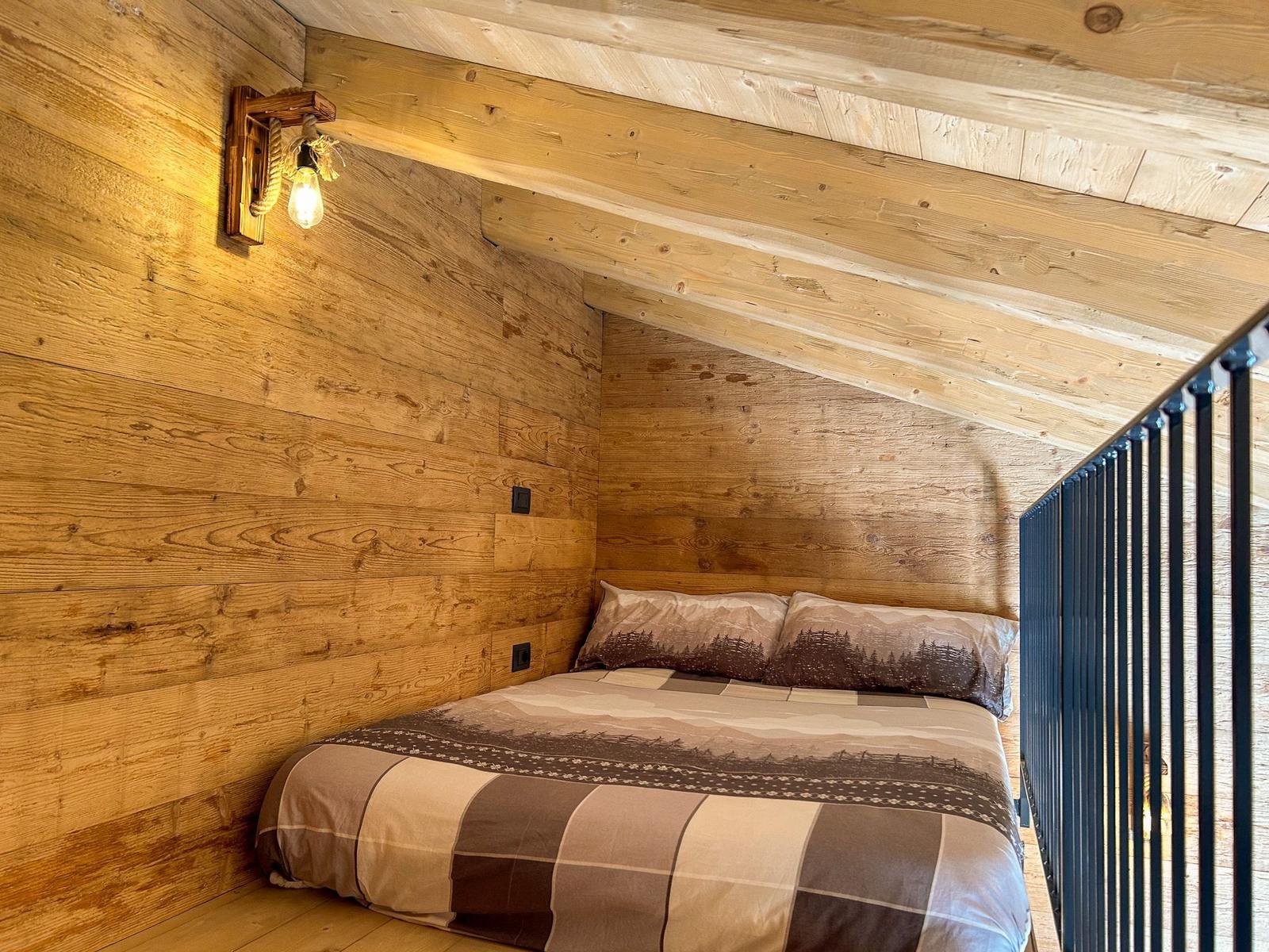 Schlafzimmer mit Holzwand, Bett und Wandlampe