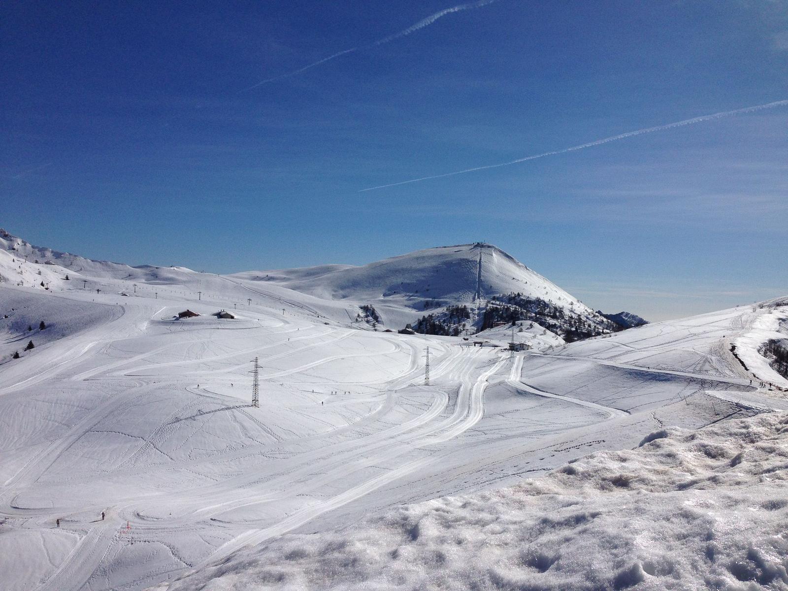 Schneekopf mit Skipisten und Berggipfel unter blauem Himmel.