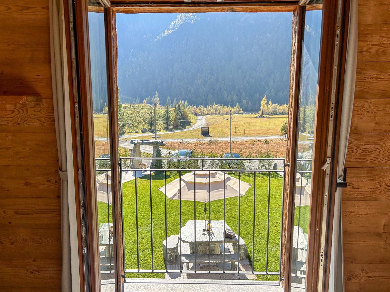Blick von Balkon auf grünen Garten und Berge.