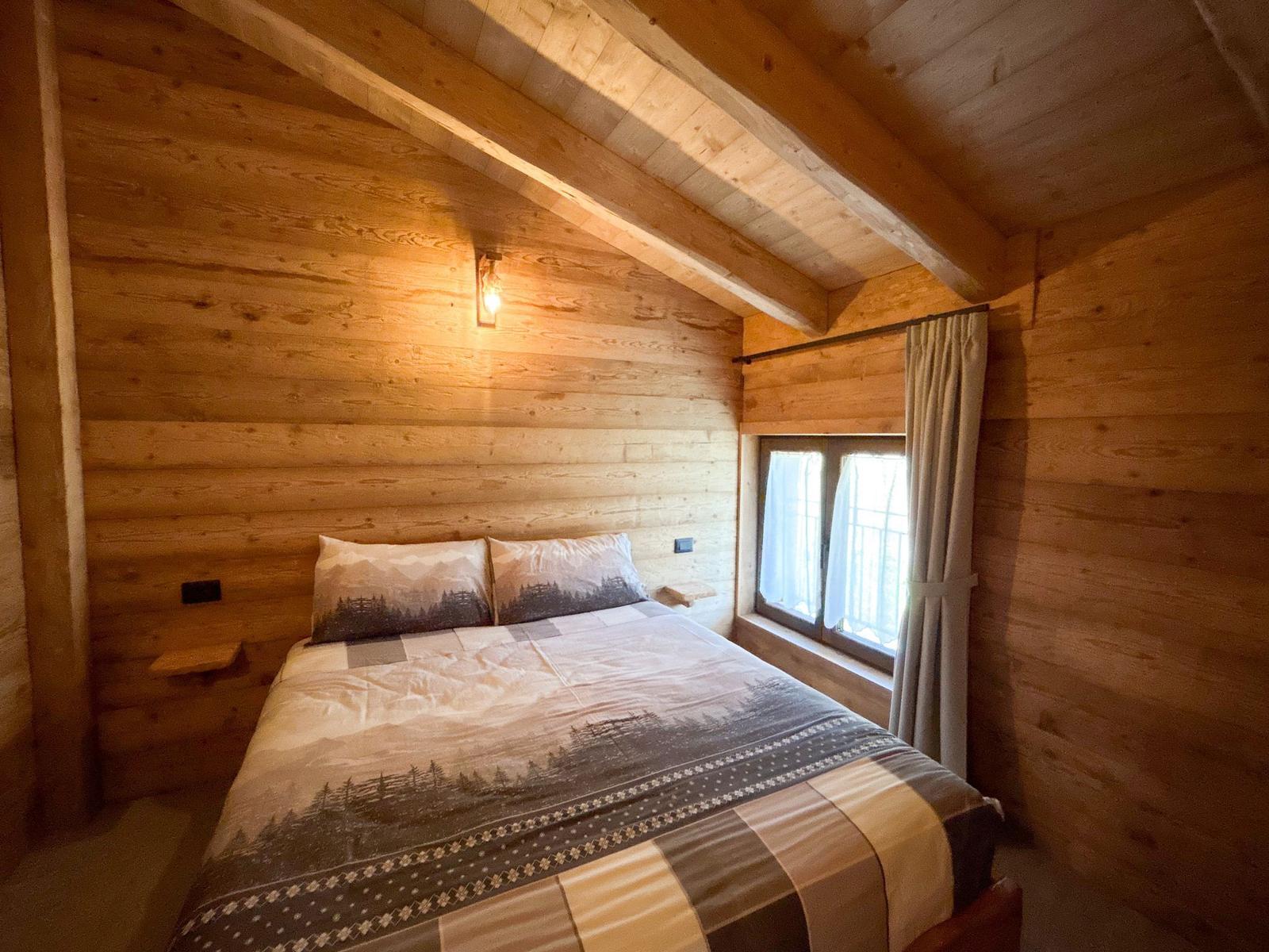 Schlafzimmer mit Holzwand, Bett und Fenster.