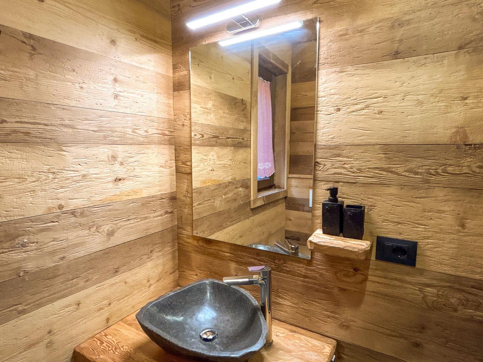 Holzbadezimmer mit Steinwaschbecken und Spiegel