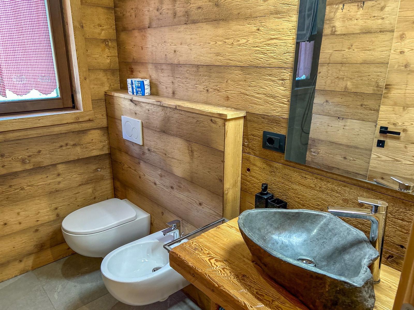 Badezimmer mit Holzwänden, Steinwaschbecken und Toilette