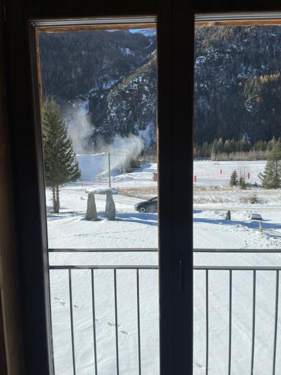 Blick vom Balkon auf schneebedeckte Landschaft mit Bäumen und Steinen.