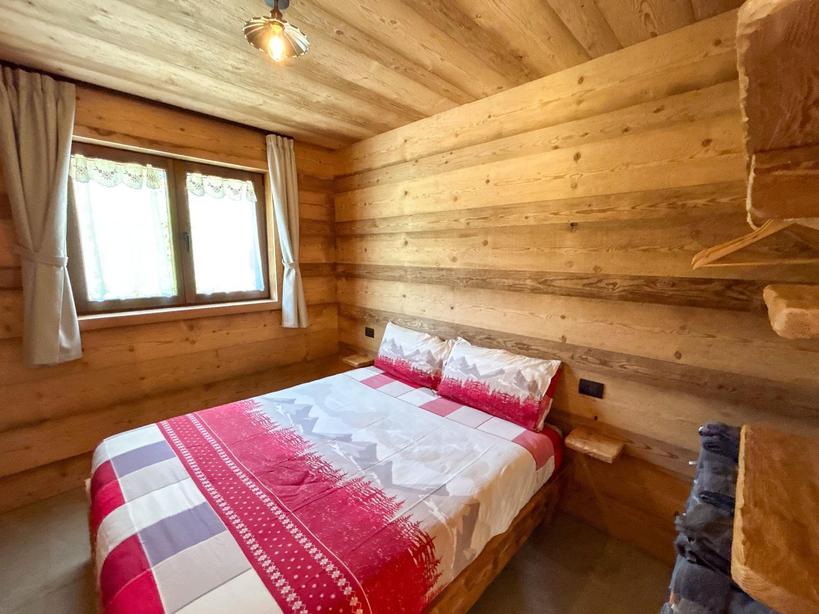 Schlafzimmer mit Holzwand, Bett und Fenster