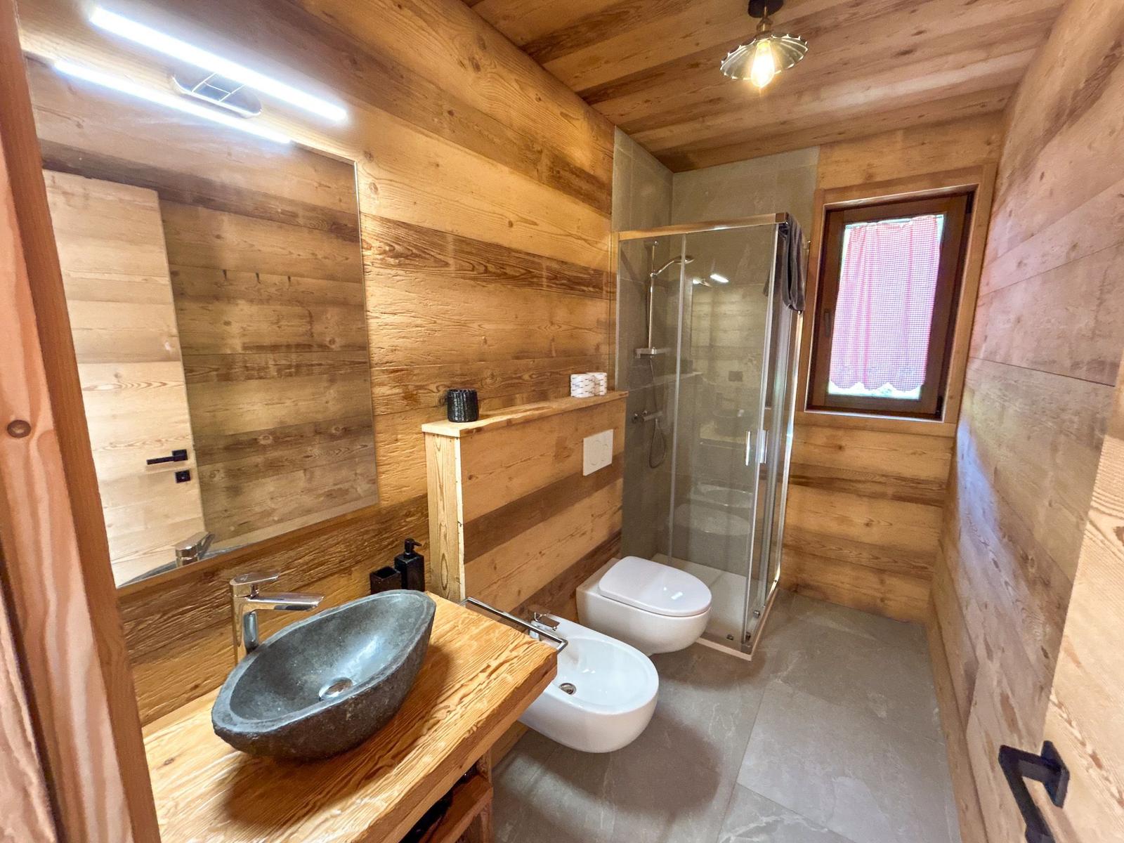 Holzbadezimmer mit Dusche, Waschbecken und Toilette.