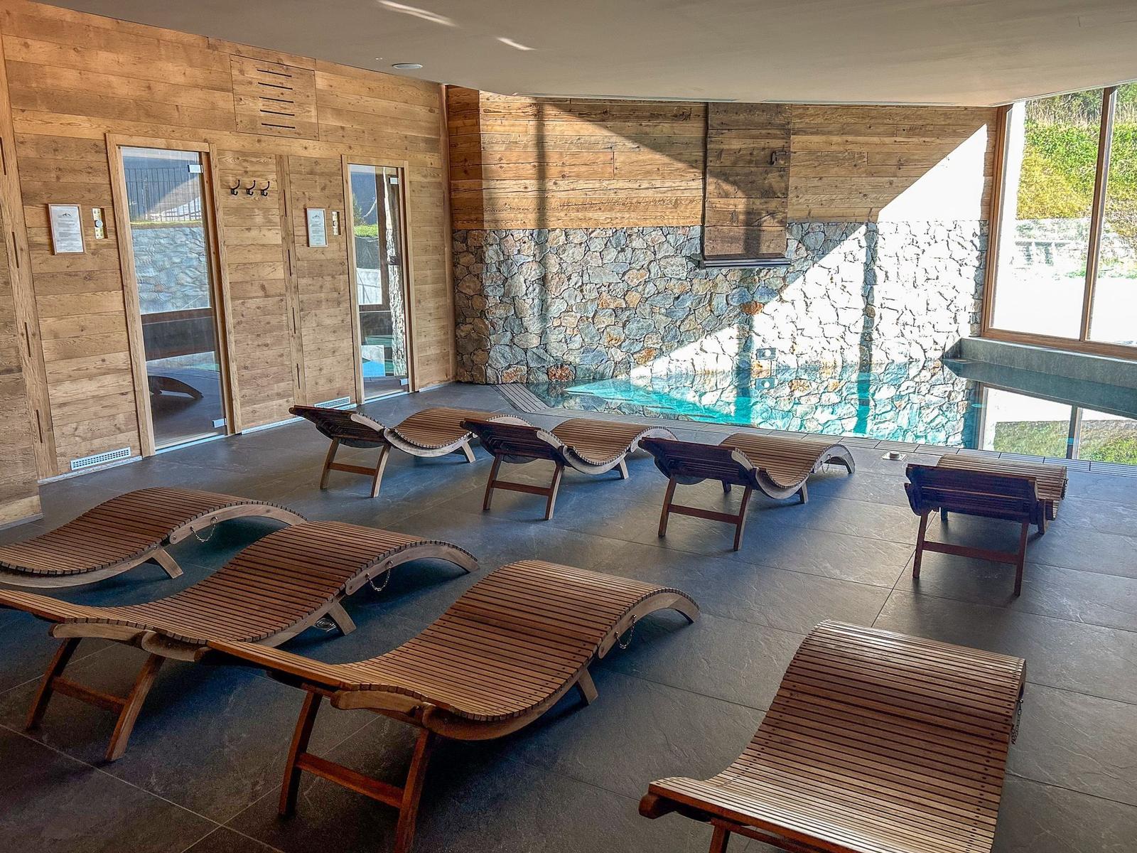 Indoor-Pool mit Holzliegen und Steinwand