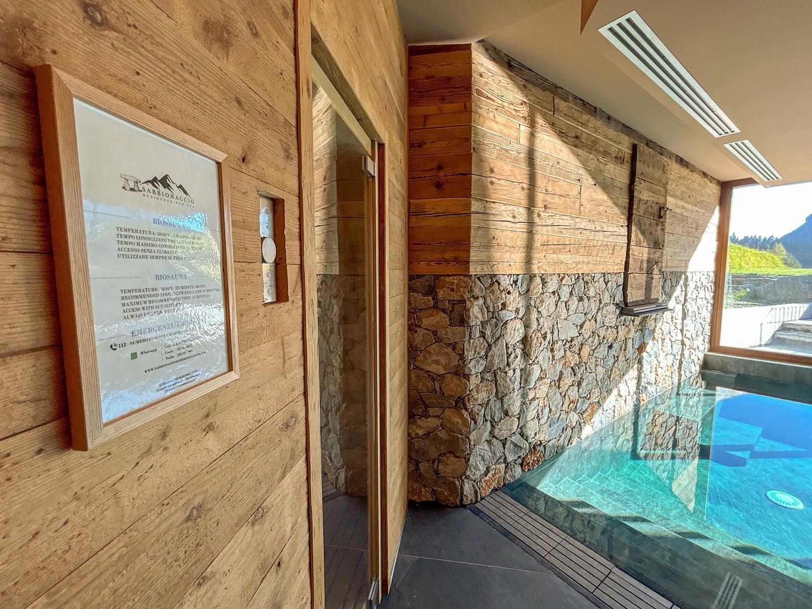 Sauna und Poolbereich mit Holzwand und Steinverkleidung. Blick auf die Berge.