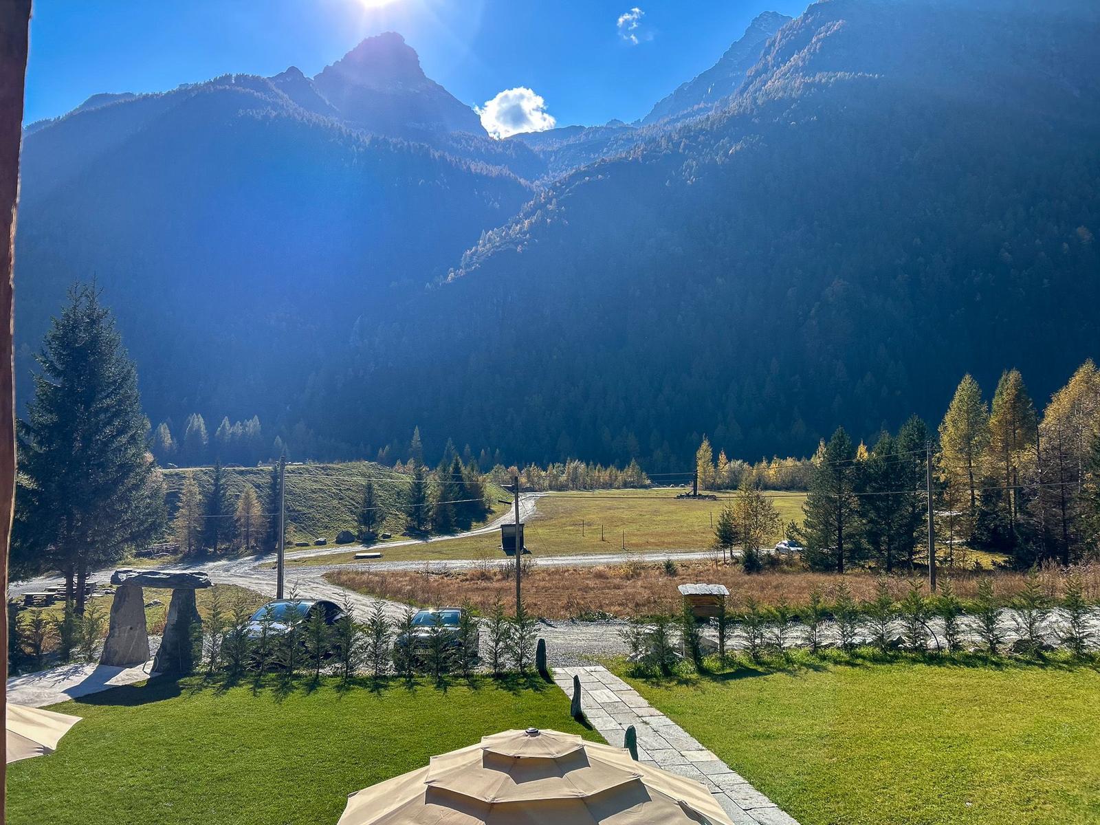 Panorama aus dem Fenster mit Bergen, Wiese und einem Zelt.