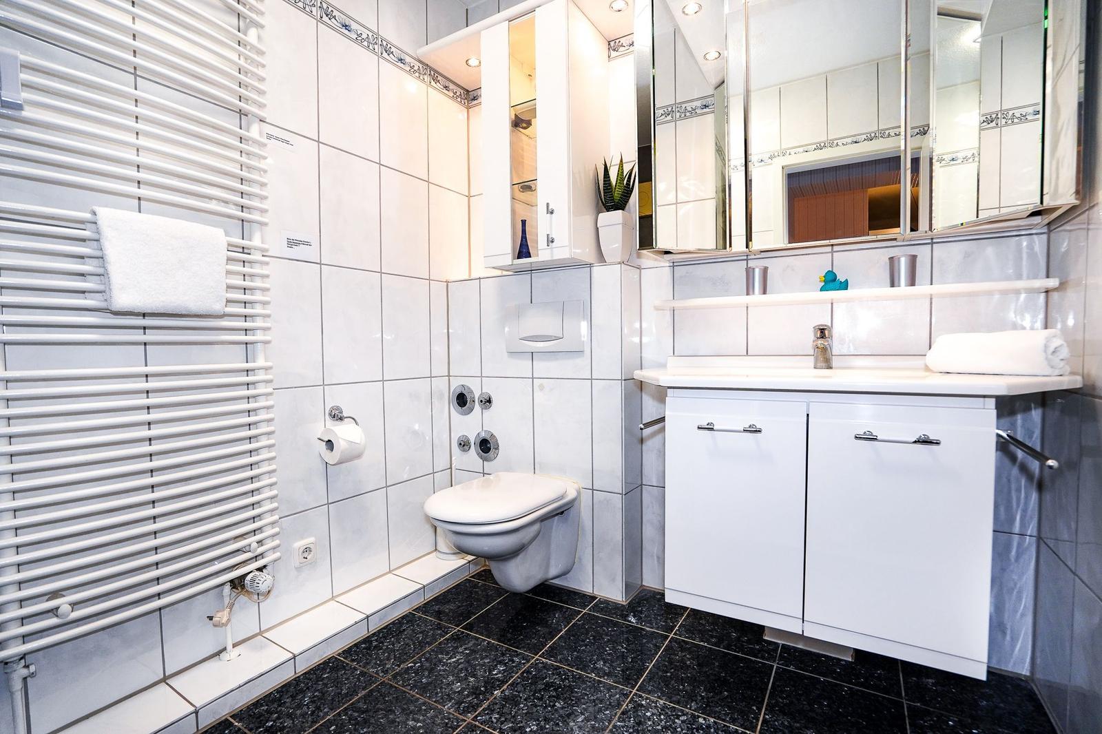 Badezimmer mit Toilette, Waschbecken und Heizkörper