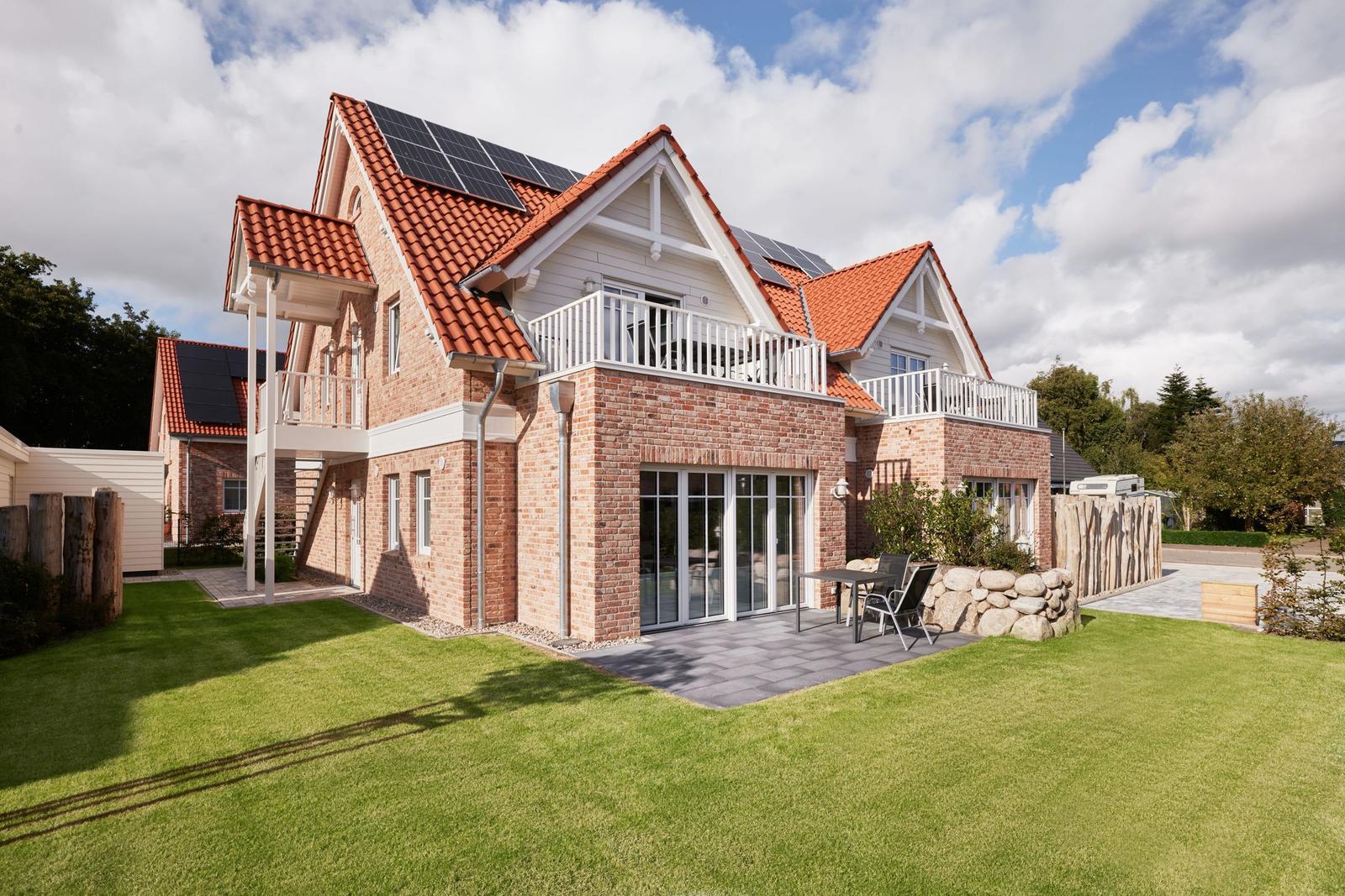 Ferienhaus mit Solaranlage, Balkon und Garten. Modernes Design mit Backsteinfassade.