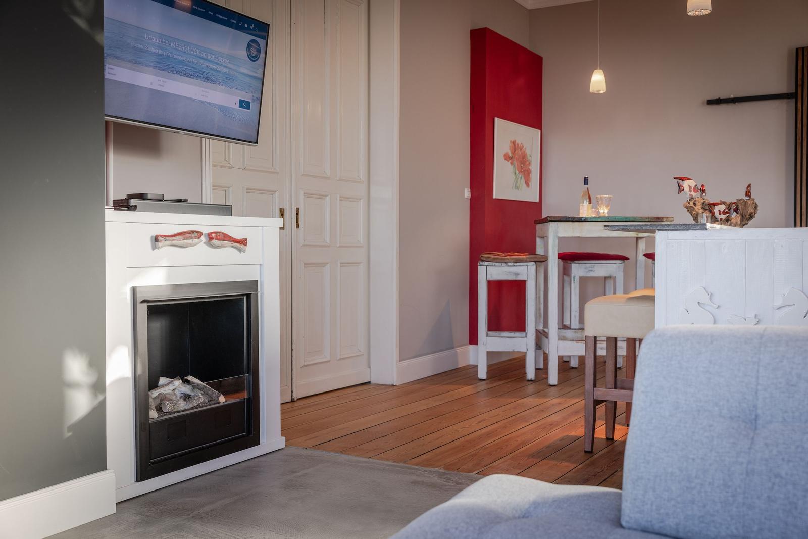 Wohnbereich mit Kamin, Fernseher und Essbereich mit Tisch und Stühlen.