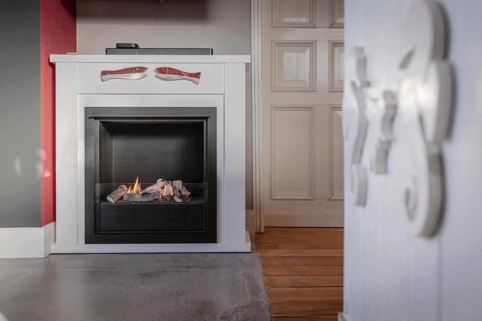 Kamin mit brennendem Holz und Fischdekoration über dem Kamin.